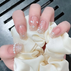 Detailed view of nude gradient press-on nails with glitter, pearls and shell fragments