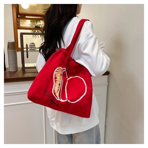 Close-up of red canvas tote bag featuring apple print and large capacity design