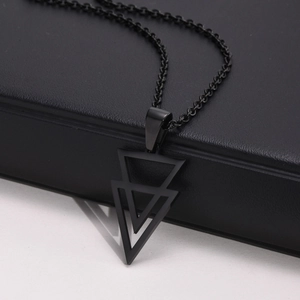 Detail of a black geometric necklace with double-layer triangle pendant on leather texture