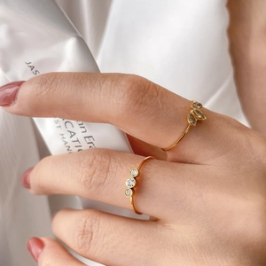 Detail of two gold rings with sparkling rhinestones and teardrop stones on fingers