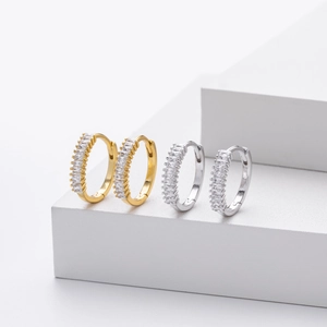 Macro shot of silver and gold geometric hoop earrings with baguette-cut cubic zirconia