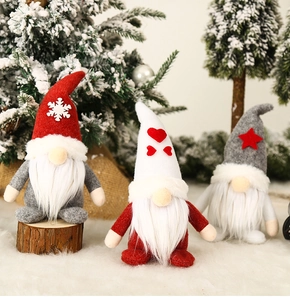 Close-up of red white and grey Christmas gnomes with knit hats on a rustic wood base