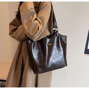 Detail of soft leather tote bag with oily texture and gold buckle on shoulder