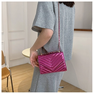 Close-up of vibrant pink patent leather crossbody bag with chic V-shape chevron quilting