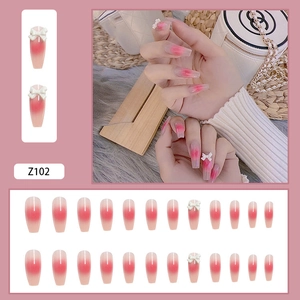 Detail of pink gradient coffin press-on nails with white bow decoration and model's hand