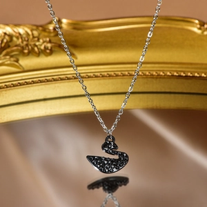 Macro shot of an elegant black swan pendant necklace with sparkling crystals on gold frame