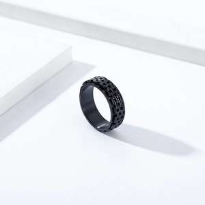 Minimalist black stainless steel spinning ring with chain texture on a white block
