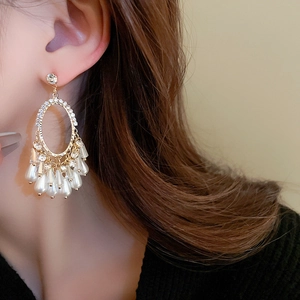 Close-up of elegant gold tassel earrings with pearls and crystals on a model