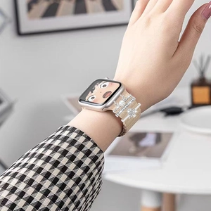 Detail of a beige braided watch band featuring silver crown and snowflake charms