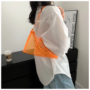 Close-up of orange clear PVC shoulder bag with plastic chain strap on a model