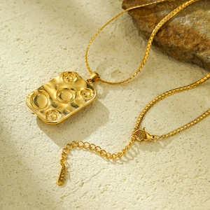 Macro detail of a gold titanium steel rectangular pendant with round textured dimples