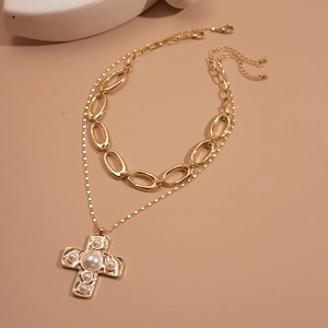 Détail du collier double doré avec pendentif croix texturé et perles incrustées