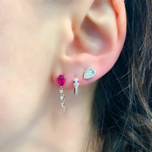 Detailed view of silver drop earrings set with red teardrop zircon and snake cuff styling