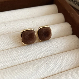 Macro view of flocking geometric heart earrings with golden frame and brown velvet texture