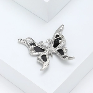Elegant silver butterfly brooch with black wings and secure pin clasp on white background