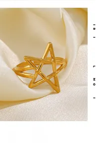 Macro detail of adjustable gold-plated star ring on a soft cream fabric background