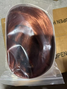 Detail view of long wavy reddish brown synthetic hair extensions in clear plastic packaging