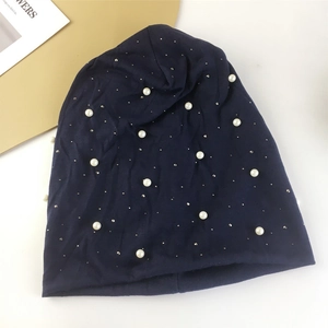 Détail du bonnet en maille bleu marine avec perles blanches et petits strass