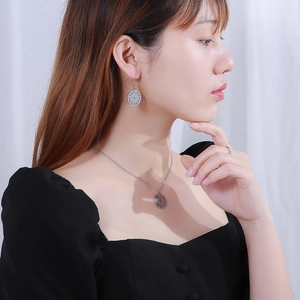 Close-up of silver hollow compass necklace and earring set on a female model