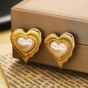 Macro shot of gold heart earrings with pearl inlay on an elegant vintage background