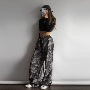 Dettaglio di pantaloni cargo mimetici grigi e di un crop top nero a maniche lunghe donna