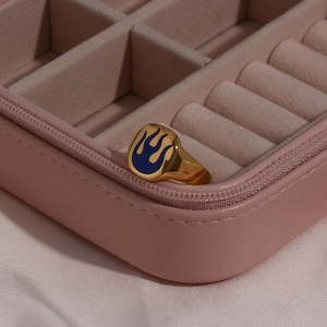Macro detail of 18K gold plated ring featuring blue enamel flame pattern on pink jewelry box