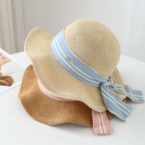 Straw sun hats with bowknot ribbons and metal tags shown from a side-angle view
