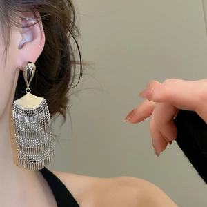 Macro view of multi-layered silver metal fringe tassel earrings worn on ear model