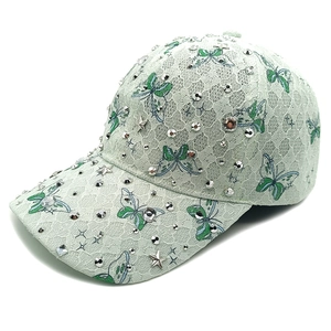 Detail der Schmetterlingsstickerei und glitzernden Strasssteine auf mintgrüner Spitzenkappe