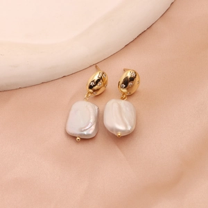 Detailed close-up of Baroque freshwater pearl earrings with star-set zircon on golden metal