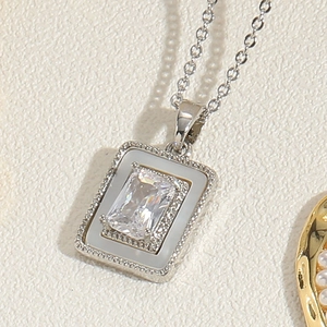 Macro detail of silver heart necklace pendant with rectangular zircon and white enamel inlay