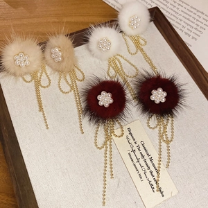 Detail of floral pompom earrings with pearls and golden tassels on display tray