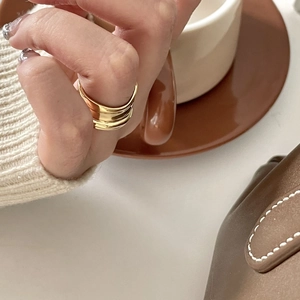 Close-up of golden multi-layer wavy ring on finger with warm lifestyle background