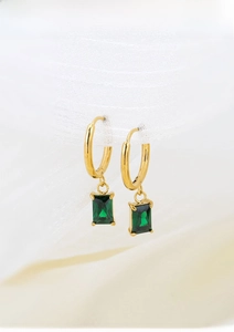 Detail of square emerald green crystal drop earrings in polished gold finish titanium