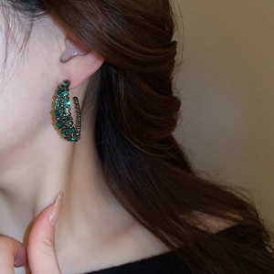 Elegant C-shaped earrings with emerald green crystals on a vintage grey metal base