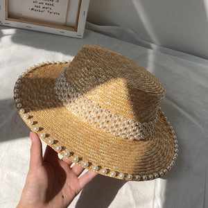 Close-up of a straw hat featuring elegant pearl embellishments and fine woven texture