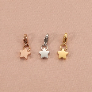 Detailed view of pentagram charms in rose gold, silver, and gold on pink fabric