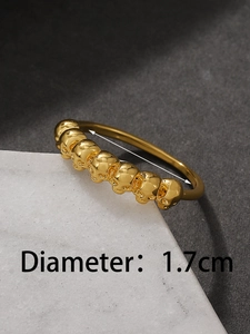 Macro shot of gold skull ring band with 1.7cm diameter measurement on marble