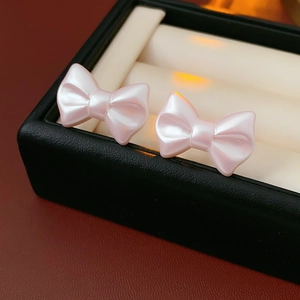 Close-up of pink bow earrings with pearl texture inside a black jewelry box