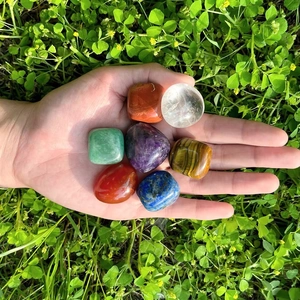 Set of seven natural polished chakra stones including amethyst and rose quartz in hand