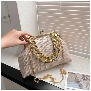 Detail of a beige pleated handbag featuring a thick gold chain handle and metal clasp