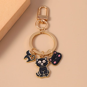 Creative black enamel cat metal keychain with gold ring and hooks on peach background