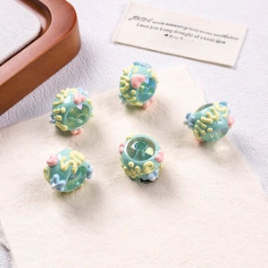 Detail of five handmade floral acrylic beads with heart patterns on a soft linen fabric