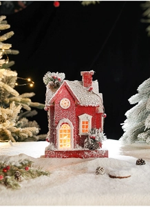 Close-up of lighted red wooden Christmas house with snow coating and berry details