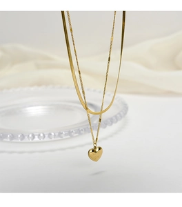 Detail of gold double-layer necklace with snake chain and Love You heart pendant