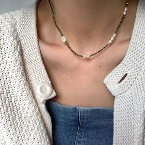 Detail shot of a Daisy Pearl Necklace with green beads on a female model's collarbone