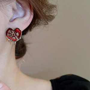 Close-up of heart-shaped rose earring with red enamel and liquid gold dripping design