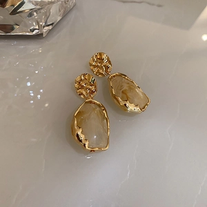 Macro view of geometric gold earrings with marble resin pendants and silver needles