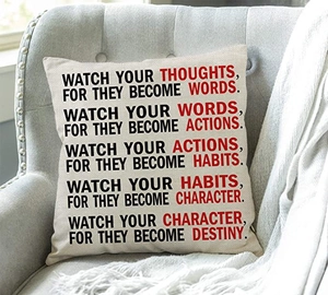 Linen quote pillowcase on grey armchair with knit blanket in a cozy room setting