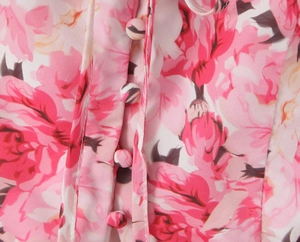 Detailed close-up of floral chiffon fabric with delicate pink prints and matching buttons